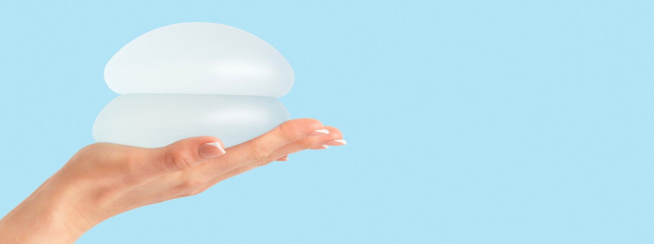 Frau hält Brustimplantate in der Hand